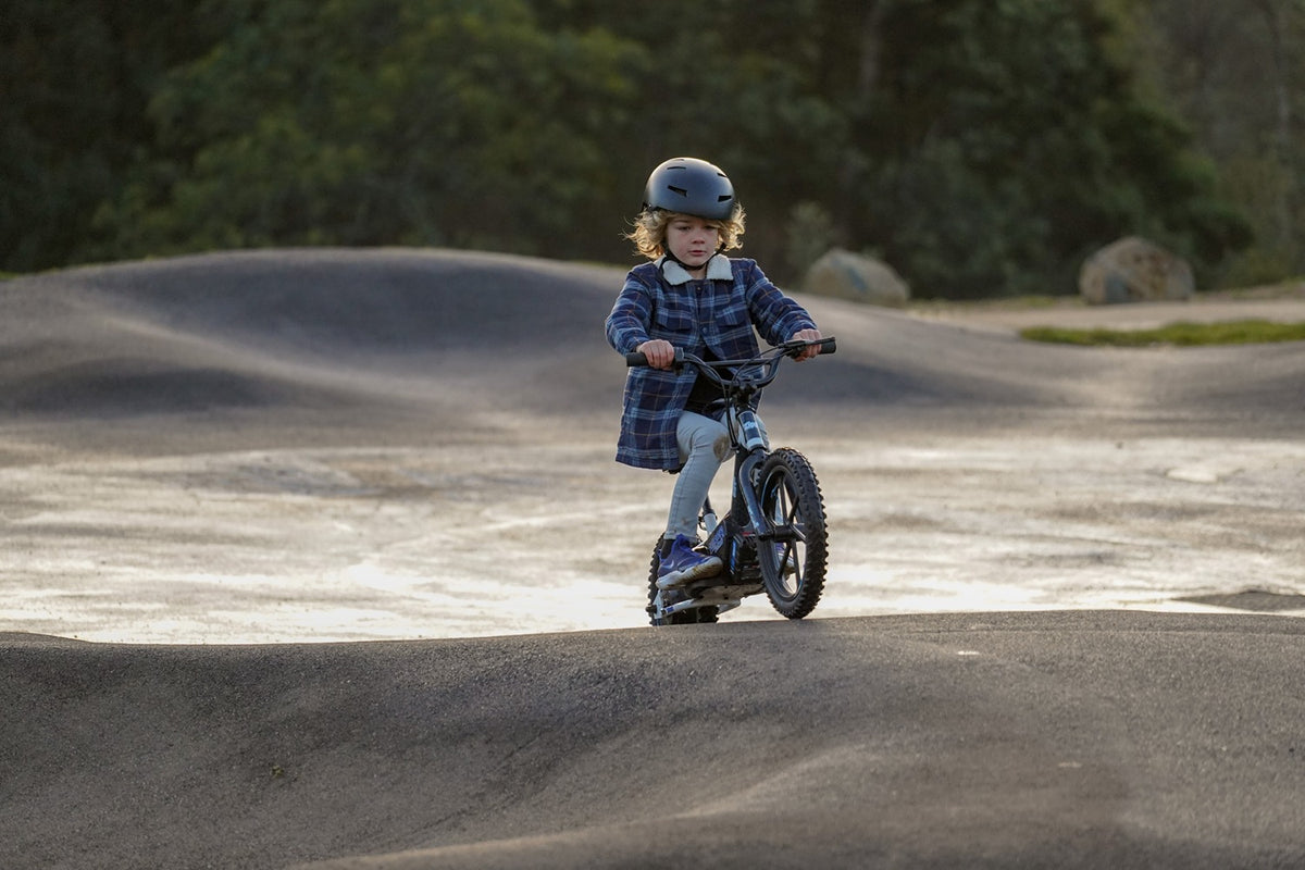 boy on zippi bike at pump track with helmet on
