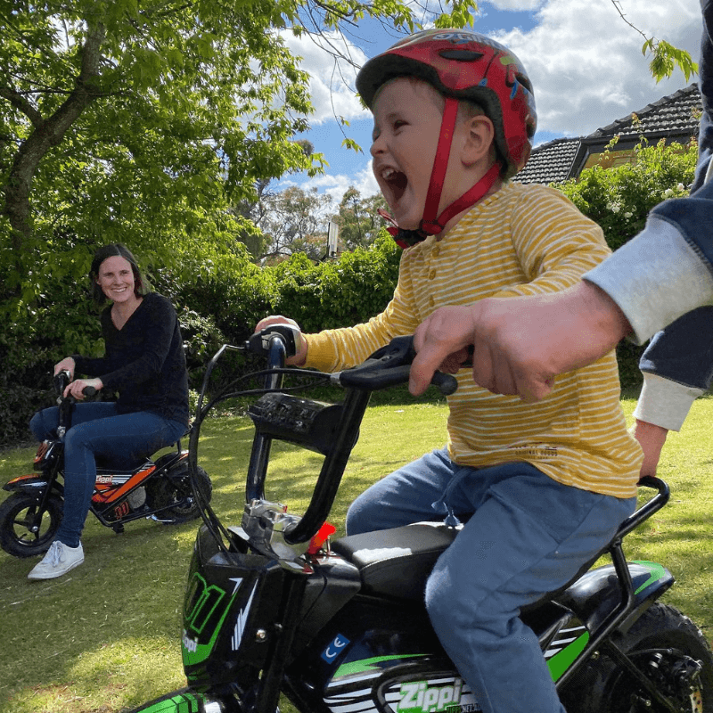 Toddler riding the Zippi Ride 10 inch in a backyard with the parent walking alongside.