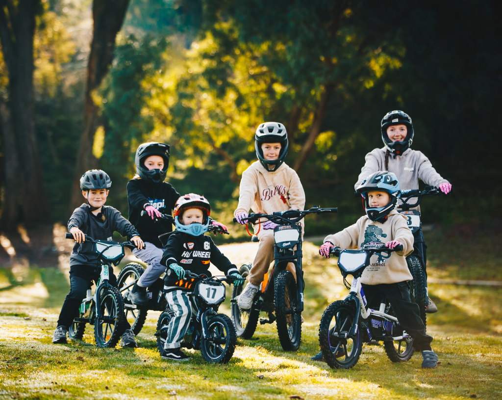 Three kids riding three sizes of Zippi bike on the riverside in Tasmania.