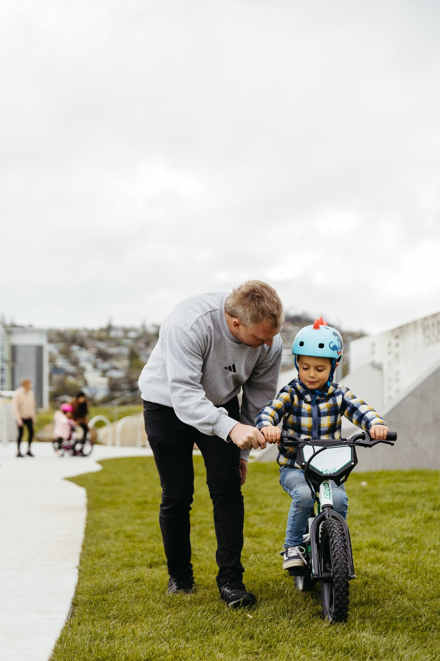 Father letting go of son's bike to help him ride solo.
