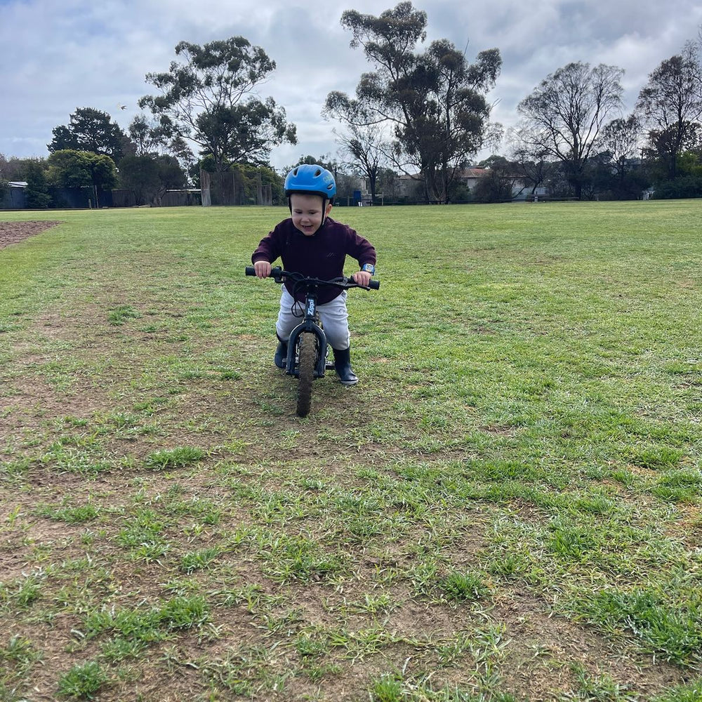 Toddler on a Zippi Rippa 12 at magic hour, tongue out, cheeky grin.