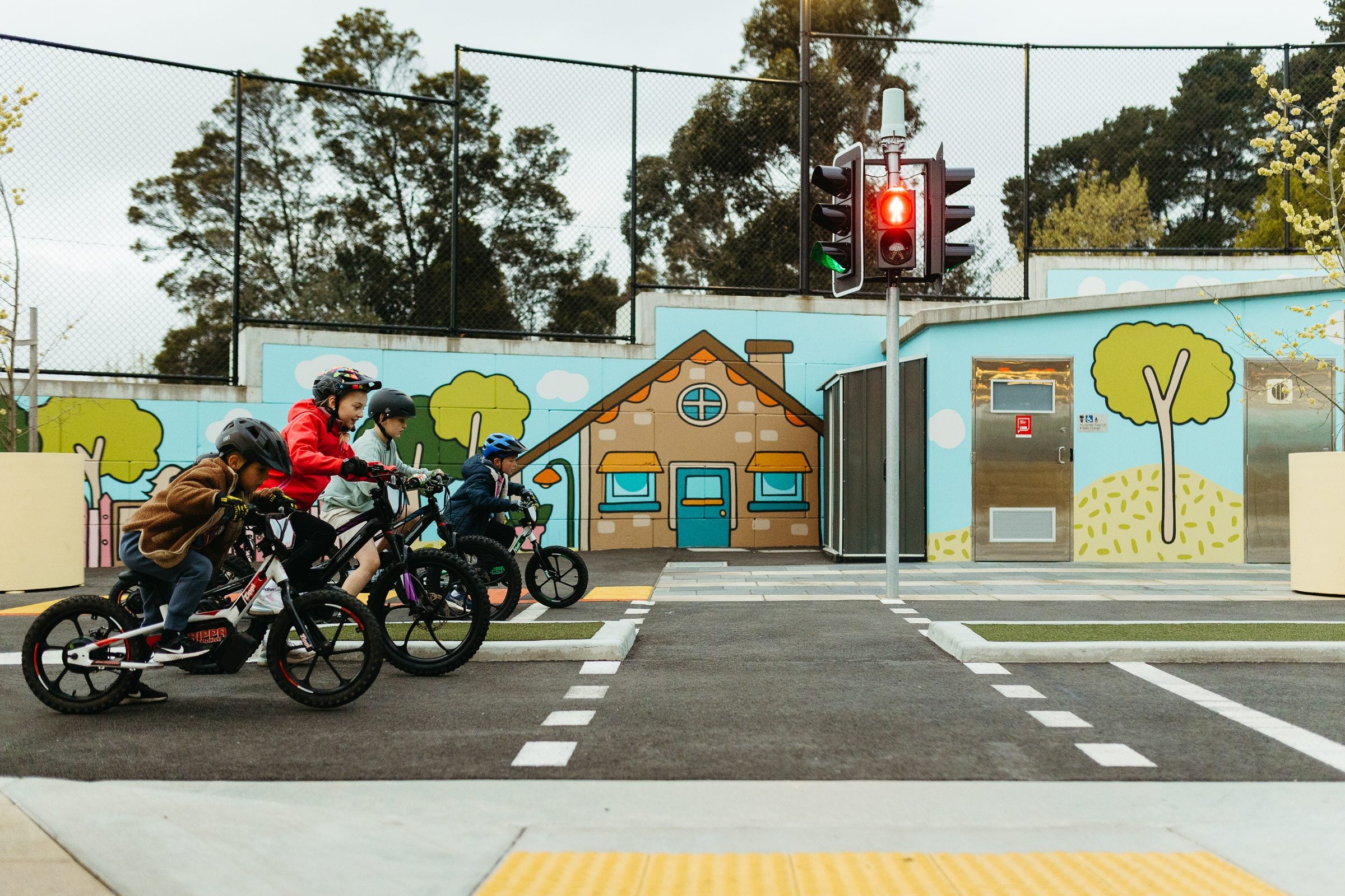 Four kids lined up on Zippi balance bikes at a traffic light, ready to ride.