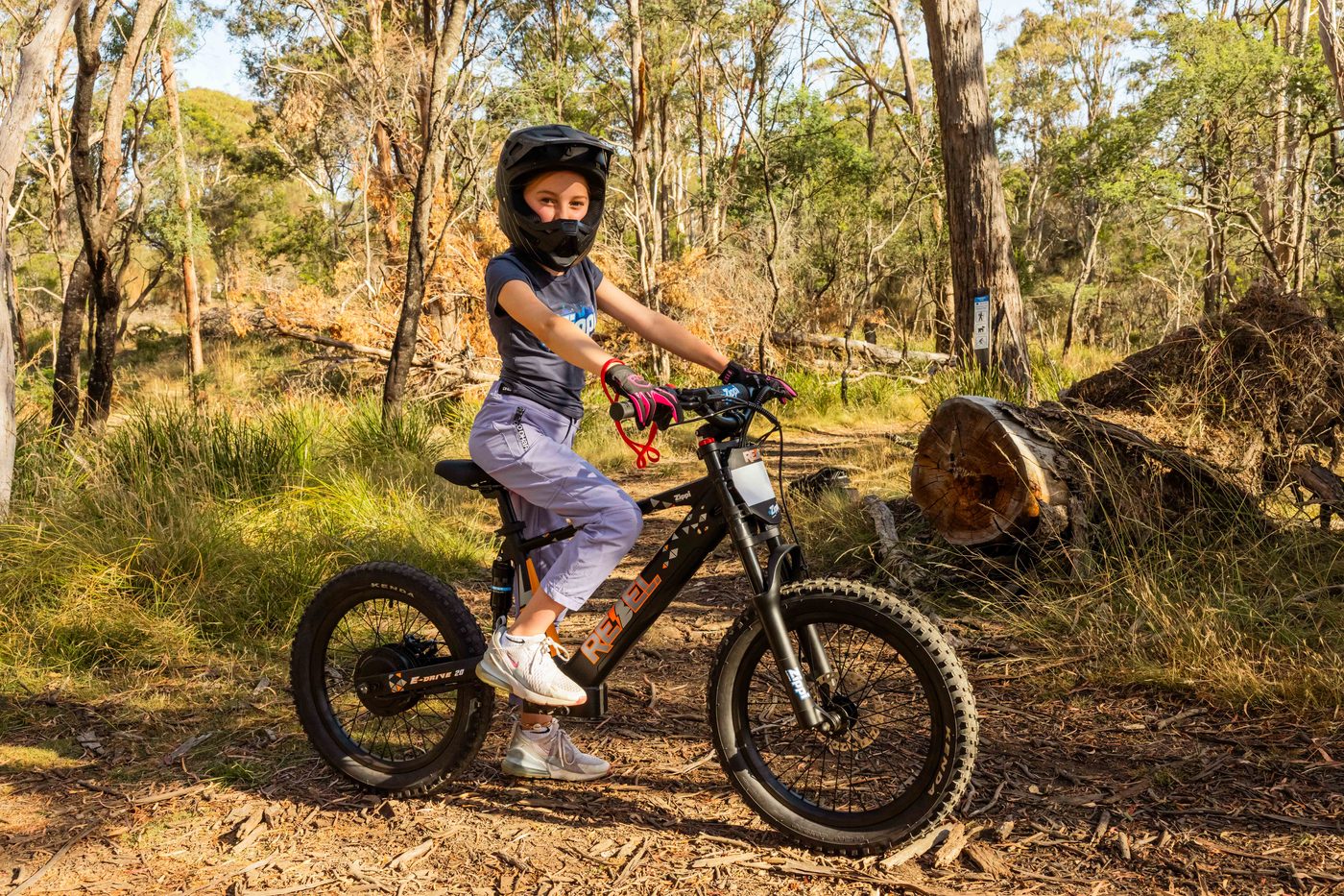 Young rider on the Zippi Rebel 20 inch Pro e-bike, full-face helmet, Tasmanian bushland trail.