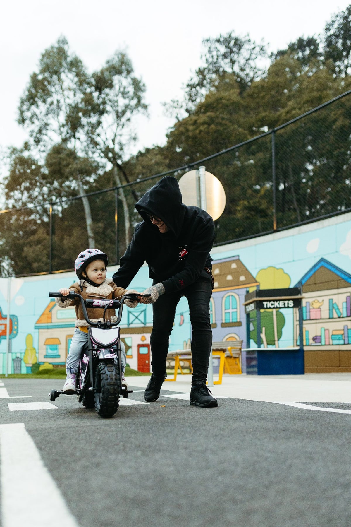 Dad helping his daughter ride the Zippi Ride 10 inch with training wheels.
