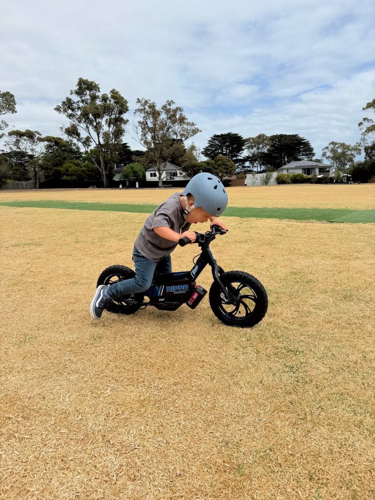 Boy mounting the Zippi Rippa e-Drive 12 inch on a dry Australian park.