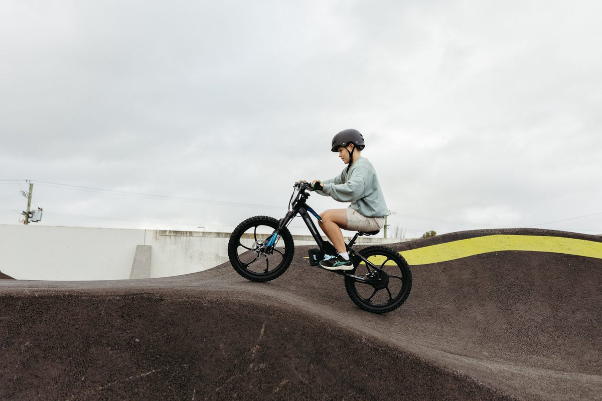 Older kid riding the Zippi Rippa e-Drive 20 inch side profile on a pump track.